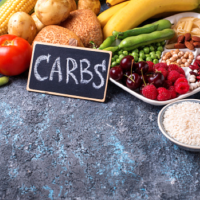 Image of fruits, bread and sign that reads 'CARBS'